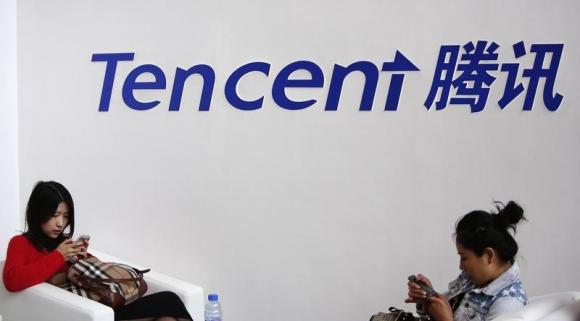 Visitors use phones underneath of logo of Tencent at Global Mobile Internet Conference in Beijing