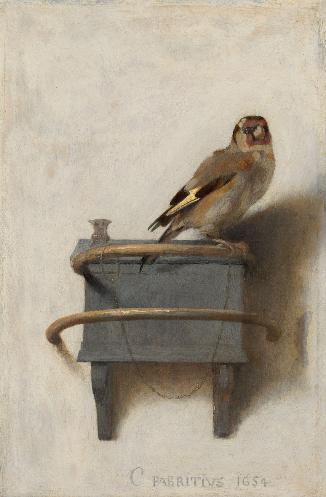 Carel Fabritius\'s The Goldfinch: a small goldfinch perched on a grey feeding box fixed to a pale plaster wall, a fine chain running from its leg to the perch