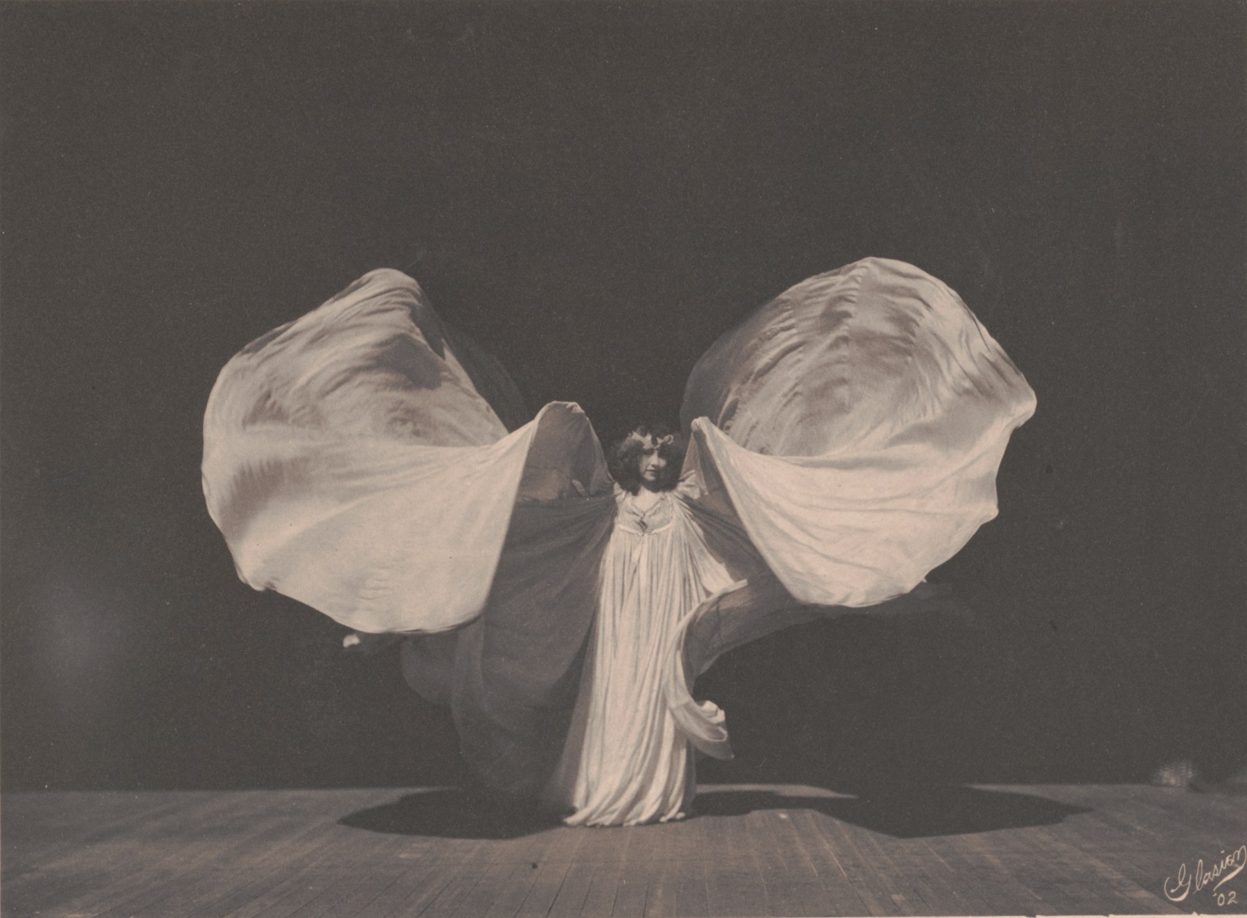Loie Fuller, photographed by Frederick W. Glasier in 1902, lifting her silk gown into two great wings